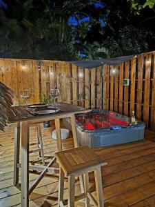 una terraza de madera con mesa, sillas y bañera de hidromasaje. en Pura vida Lodge en Sainte-Rose