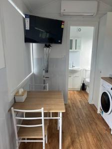 a small kitchen with a table and a washing machine at Sweet Cute blue tiny home with Pool and 2 minute drive to the beach in Wollongong