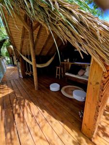 Cabaña con techo de paja y terraza de madera con hamaca en Pura vida Lodge en Sainte-Rose