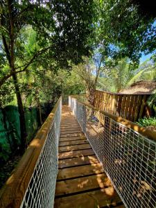 un puente peatonal de madera en un bosque con árboles en Pura vida Lodge, en Sainte-Rose