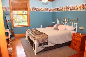 Dormitorio azul con cama y ventana en Headlands Estate, en Whanganui