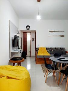uma sala de estar com um sofá amarelo e uma mesa em Apartamento Ubatuba Maranduba 150m da Praia em Ubatuba