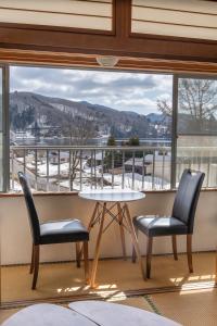 two chairs and a table in front of a window at Elan Hotel Lake Nojiri in Shinano