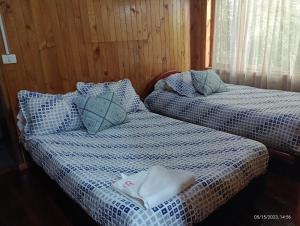duas camas sentadas uma ao lado da outra num quarto em cabañas Arcoíris del lago Nº 2 em Pasto