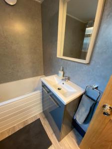a bathroom with a sink and a mirror and a tub at Comfortable 2 bedroom home from home with parking in Nottingham