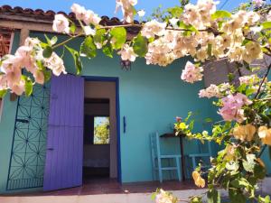 a blue house with a purple door and flowers at Chalé Flor do Ser in Canoa Quebrada