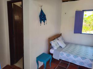 a small room with a bed and a blue stool at Chalé Flor do Ser in Canoa Quebrada