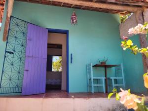an open door to a house with blue and purple walls at Chalé Flor do Ser in Canoa Quebrada