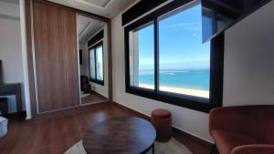 een woonkamer met een tafel en uitzicht op de oceaan bij Tanger Luxury Family Appartments, Boulevard. in Tanger