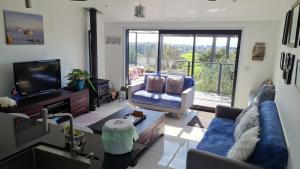 a living room with a blue couch and a tv at Cosy Country Cottage on a Sunny Hill in New Plymouth