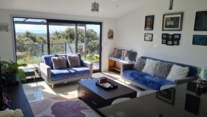 a living room with two couches and a table at Cosy Country Cottage on a Sunny Hill in New Plymouth