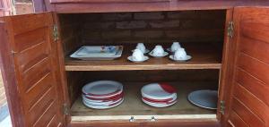 een houten kast gevuld met borden, bekers en borden bij Casa Temporada Guriri Beira-Mar in Guriri