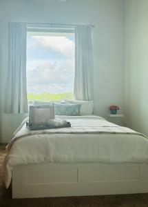 a bed with a laptop on it in front of a window at The Tiny Village Couple Retreat in Cabo Rojo