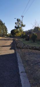 Pretoria的住宿－Rose Guest House，一条鹅卵石街道,有石墙和树木