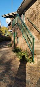 eine grüne Treppe an der Seite eines Backsteingebäudes in der Unterkunft Rose Guest House in Pretoria