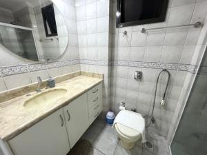 a bathroom with a sink and a toilet and a mirror at Apartamento 3 quartos e boas energias in Balneário Camboriú