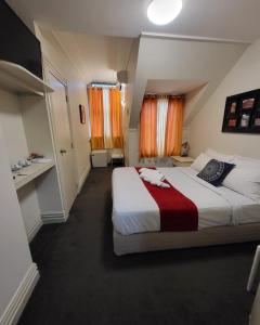 a bedroom with a large bed and orange curtains at The Shakespeare Hotel in Auckland