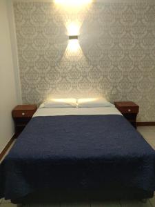 Un dormitorio con una cama azul y una luz en la pared en La Posada Norteña, en Lambayeque