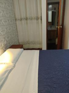a bedroom with a bed and a bathroom with a mirror at La Posada Norteña in Lambayeque