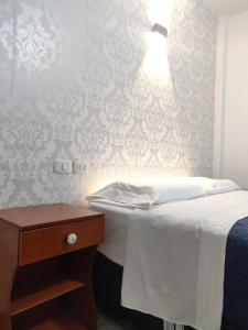 1 dormitorio con 1 cama y 1 lámpara en la pared en La Posada Norteña, en Lambayeque