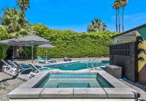 een zwembad met 2 stoelen en een parasol bij Bright & Harmonious Oasis - A Ryson Property in Palm Springs