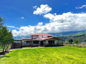 a house with a green lawn in front of it at Casa de campo con hermosa vista in Riobamba