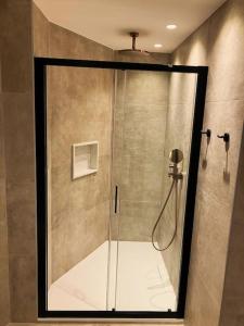 La salle de bains est pourvue d'une douche avec une porte en verre. dans l'établissement Villa with pool and sea view with two independent floors, à Faro