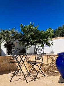 2 Stühle, ein Tisch und eine blaue Vase in der Unterkunft Villa with pool and sea view with two independent floors in Faro