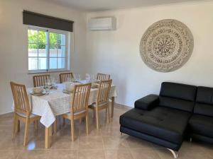 a dining room with a table and a couch at Villa with pool and sea view with two independent floors in Faro