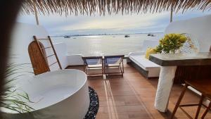a balcony with a bathtub and chairs and the water at บ้านมัจฉา in Ko Larn