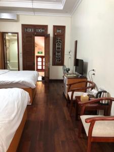 a room with two beds and a desk and a television at Maya Homestay in Hue