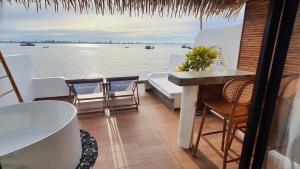 a balcony with chairs and a table and a view of the water at บ้านมัจฉา in Ko Larn
