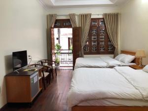a hotel room with two beds and a television at Maya Homestay in Hue