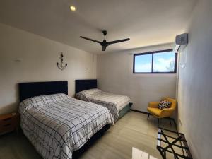a bedroom with two beds and a chair and a window at OLEA Beach Condos en Chicxulub Puerto in Chicxulub +22 photos