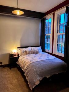 ein Schlafzimmer mit einem Bett und zwei Fenstern in der Unterkunft The Bolt Hole in Stratford-upon-Avon