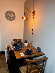 a wooden table with chairs and a clock on the wall at The Bolt Hole in Stratford-upon-Avon