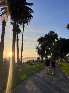 洛杉磯的住宿－Cozy Santa Monica getaway steps to the beach Free Parking，两个人沿着棕榈树的道路走