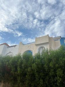 un bâtiment bien exposé avec un ciel bleu et quelques buissons dans l'établissement Oocka stay villas, à Dahab