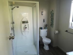 a bathroom with a toilet and a glass shower door at Houhora Harbour Haven in Pukenui