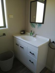 a bathroom with a white sink and a mirror at Houhora Harbour Haven in Pukenui
