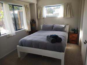 a bedroom with a white bed with two windows at Houhora Harbour Haven in Pukenui