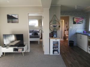 a living room with a kitchen and a living room with a tv at Houhora Harbour Haven in Pukenui