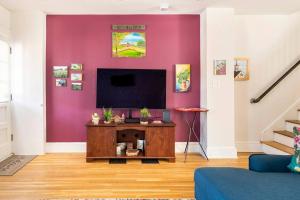 sala de estar con TV en una pared púrpura en 3 minutes to downtown w/Patio, Art, Fire Pit, BBQ, en Lancaster