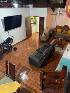 sala de estar con sofá de cuero negro y TV de pantalla plana en Hermosa villa Renacer, en Concepción de La Vega