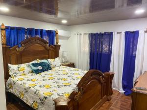 1 dormitorio con cama de madera y cortinas azules en Hermosa villa Renacer, en Concepción de La Vega