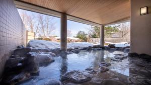 a pond with rocks in the middle of a building at Satoyama Auberge & Hot Spring Wellness Spa Sakuragaike Kurgarden in Nanto