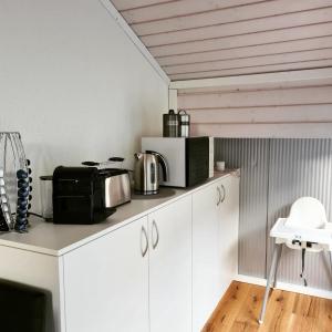 una cocina con armarios blancos, microondas y electrodomésticos en Muota River & Industry Apartment by Nature Apartments Switzerland en Muotathal