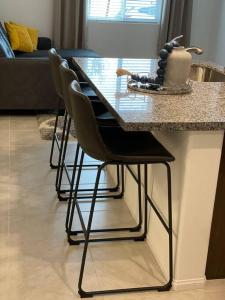 a kitchen island with four bar stools at a counter at Sleek & Stylish 3-BR Luxury Townhome - 7 Mile from Las Vegas Strip in Las Vegas