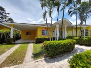una casa amarilla con palmeras delante en Hotel y villas palma Real ., en La Ceiba