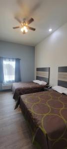 a room with two beds and a ceiling fan at Bungalows Hotel & Hotel Que at Lakeline Austin Cedar Park in Cedar Park
